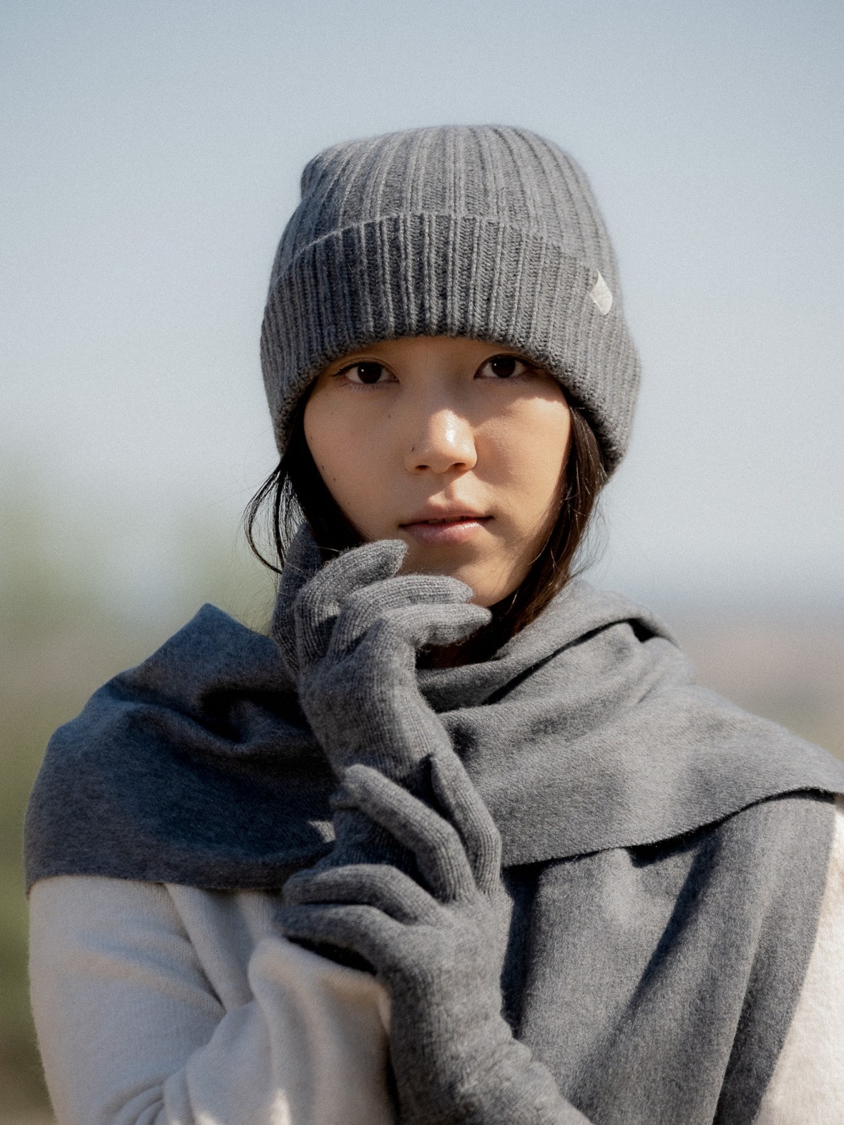 Suvd derby grey cashmere gloves worn with a matching grey ribbed beanie and scarf
